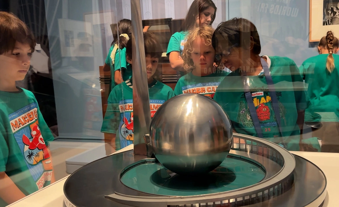 A group of children in a museum gallery looking at an object in a glass case