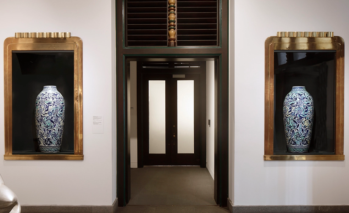 Interior room looking into another room with two display cases holding ceramic vases on either side of the doorway