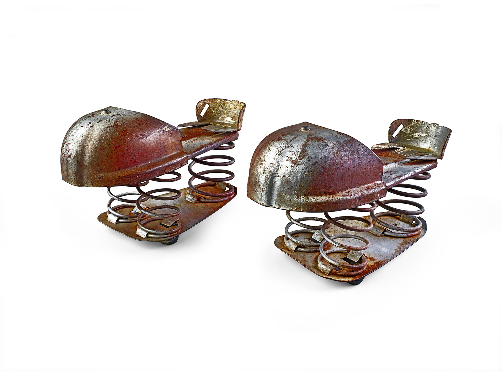 Two rusted metal shoe-shaped objects with rounded toe covers and exposed coil springs