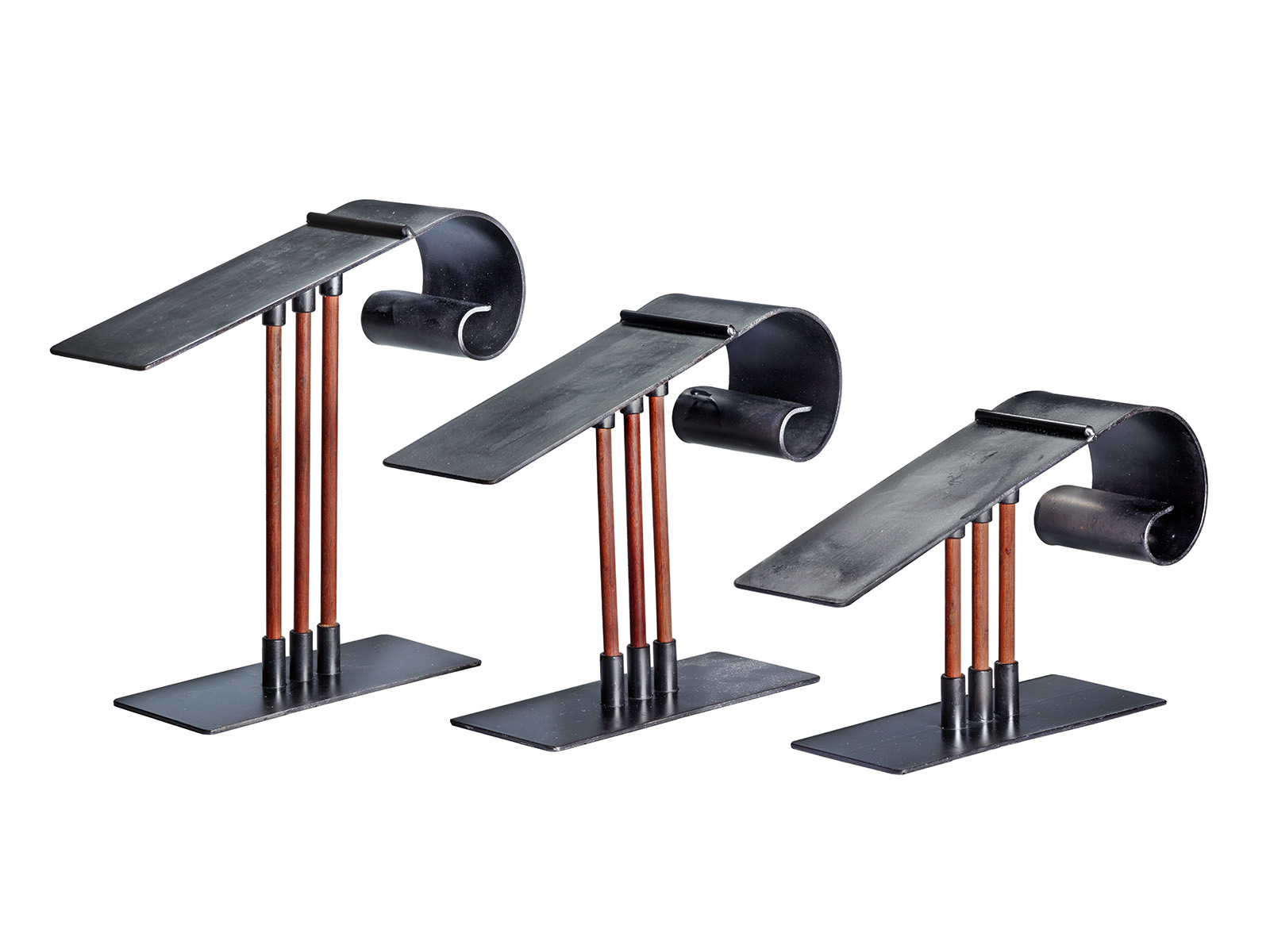 Three black metal stands with long flat tops, curved supports, and narrow wooden rods