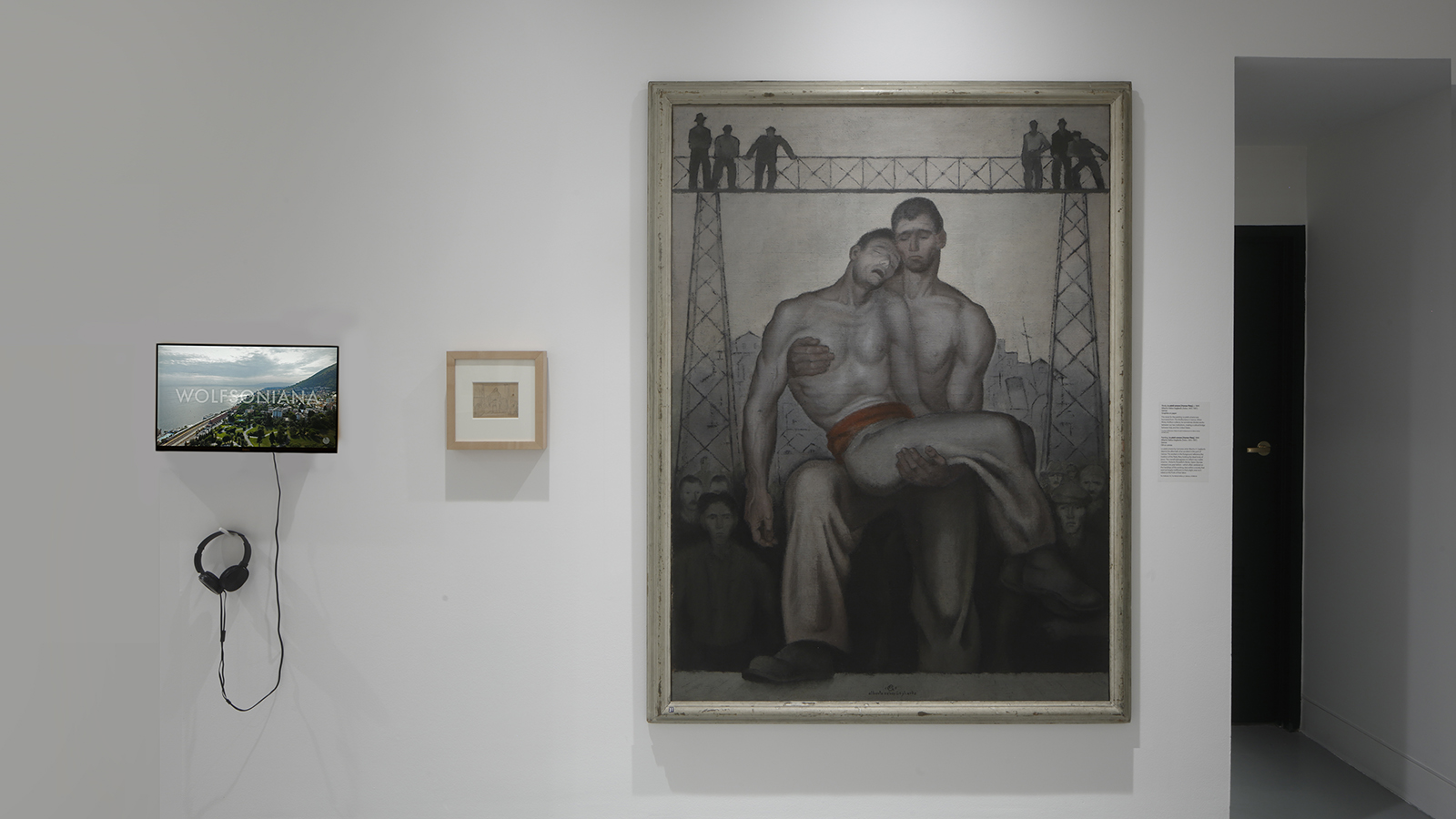 Gallery wall with a large painting of two figures, a small framed drawing, and a video monitor with attached headphones.